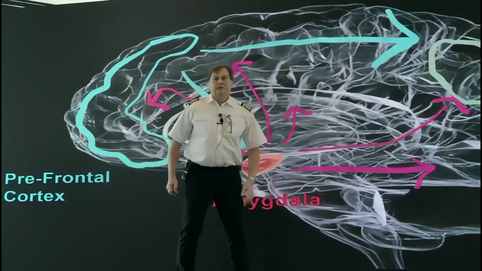 Peter on stage in front of a brain scan showing the pre-frontal cortex